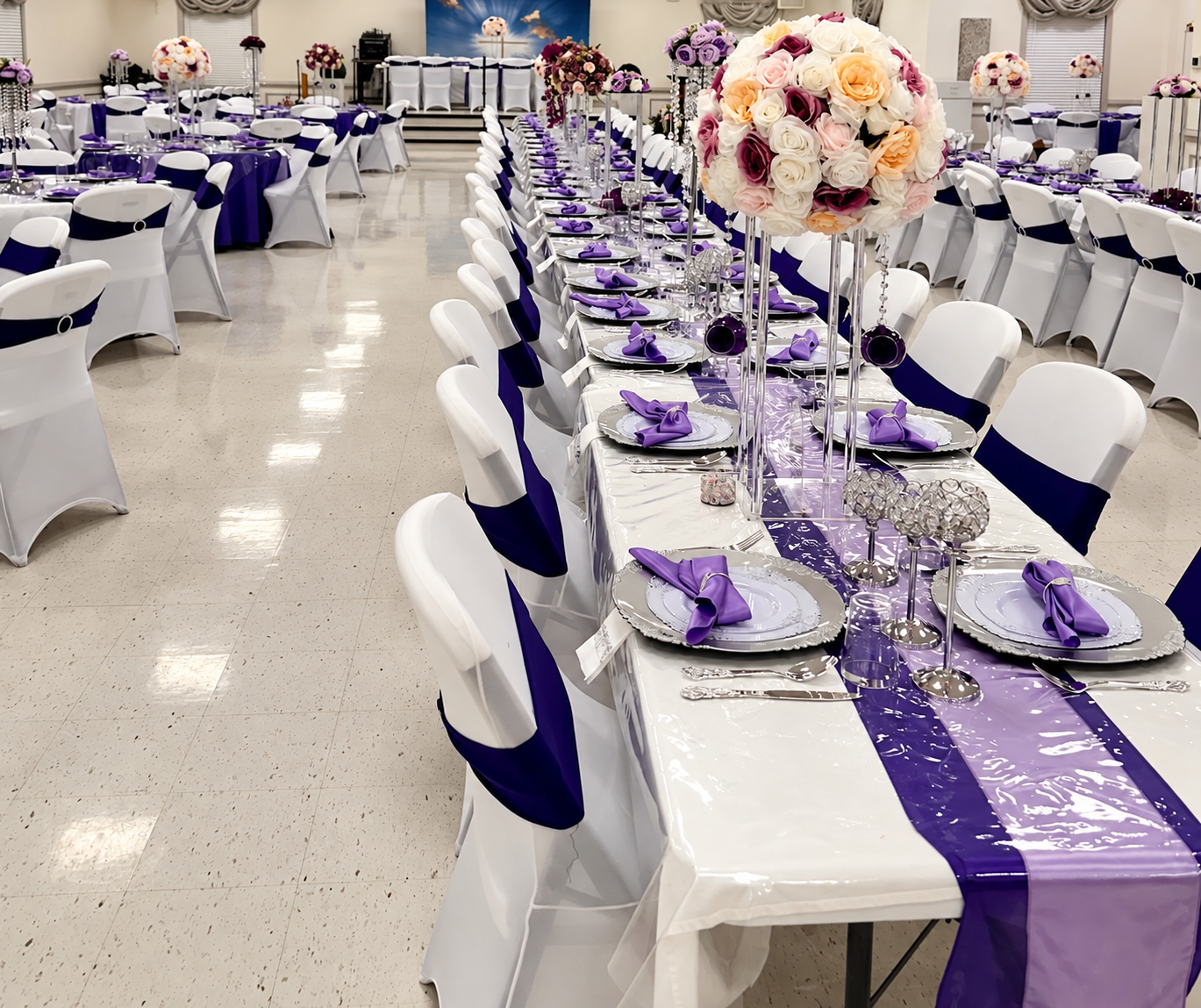 Pastoral installation reception with purple and white tables, floral focal points, and a clear center aisle